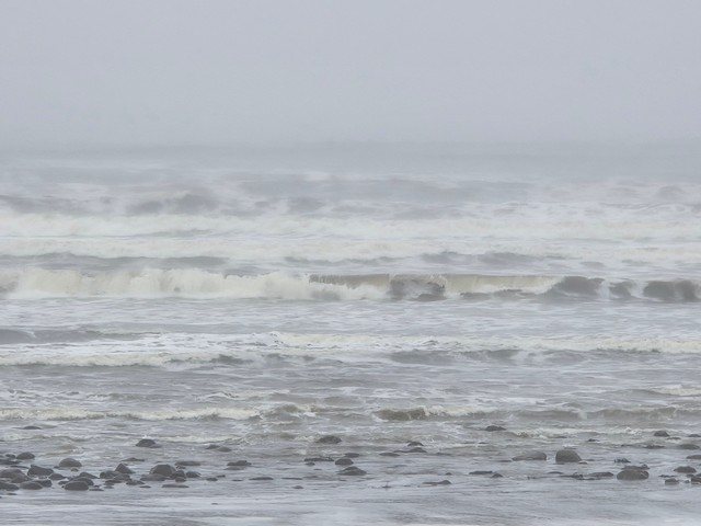 Kite surfer out the back as a group of beginner surfers face a lot of white water in the shallows